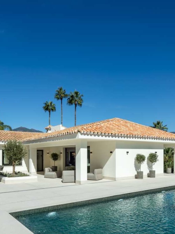A luxurious Andalusian-style villa with modern smart home features, surrounded by lush gardens and scenic mountain views. The property blends traditional Spanish architecture with contemporary elegance, featuring white stucco walls, arched doorways, and a serene outdoor living space.