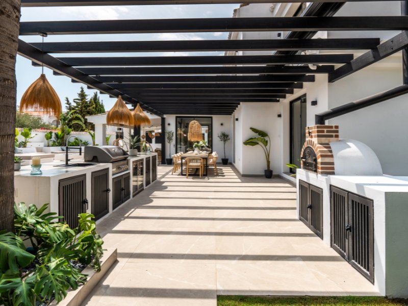 Outdoor BBQ area in a cozy beach villa, just steps from the sea, featuring a built-in grill, stylish seating, and a relaxed, coastal-inspired design, offering the perfect space for outdoor dining and entertaining with ocean views.