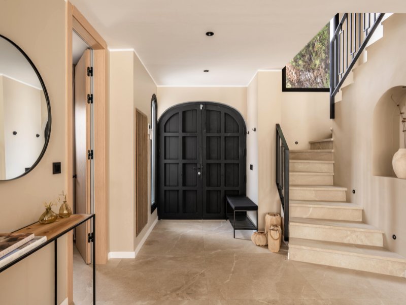 Welcoming entrance hall of a cozy beach villa, just steps from the sea, featuring a spacious, bright design with natural materials, large windows that allow for ample light, and a seamless flow into the open living spaces, setting the tone for coastal living.