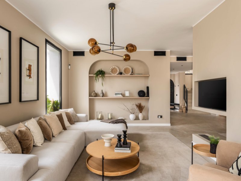 Charming living room in a cozy beach villa, just steps from the sea, featuring comfortable, modern furnishings, large windows that flood the space with natural light, and a relaxed, coastal-inspired design that connects seamlessly with the ocean views outside.
