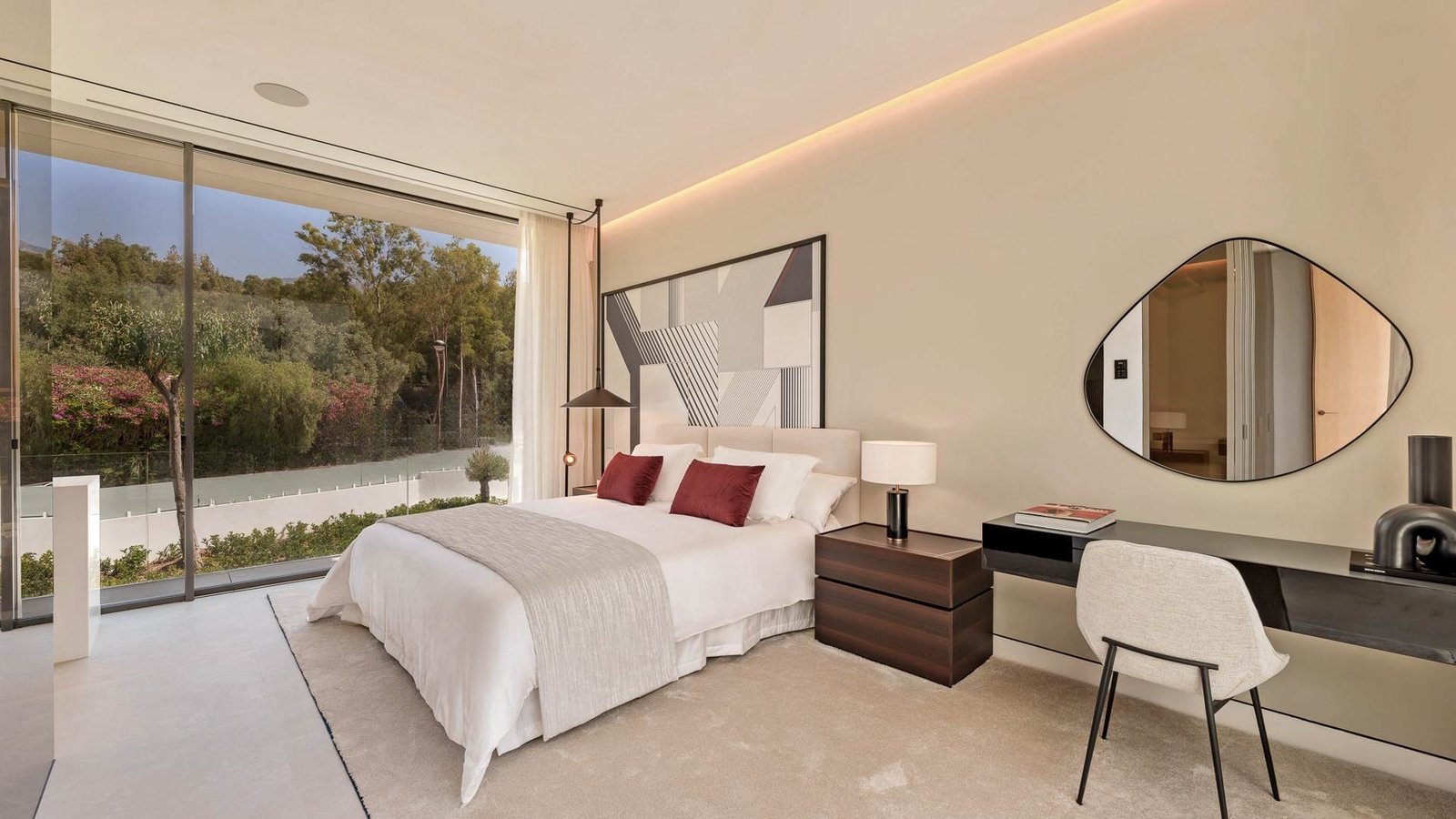 A luxurious bedroom with large windows offering stunning views of the surrounding landscape. The room features a king-size bed, sophisticated decor in neutral tones, and soft ambient lighting, creating a serene and elegant atmosphere perfect for relaxation.