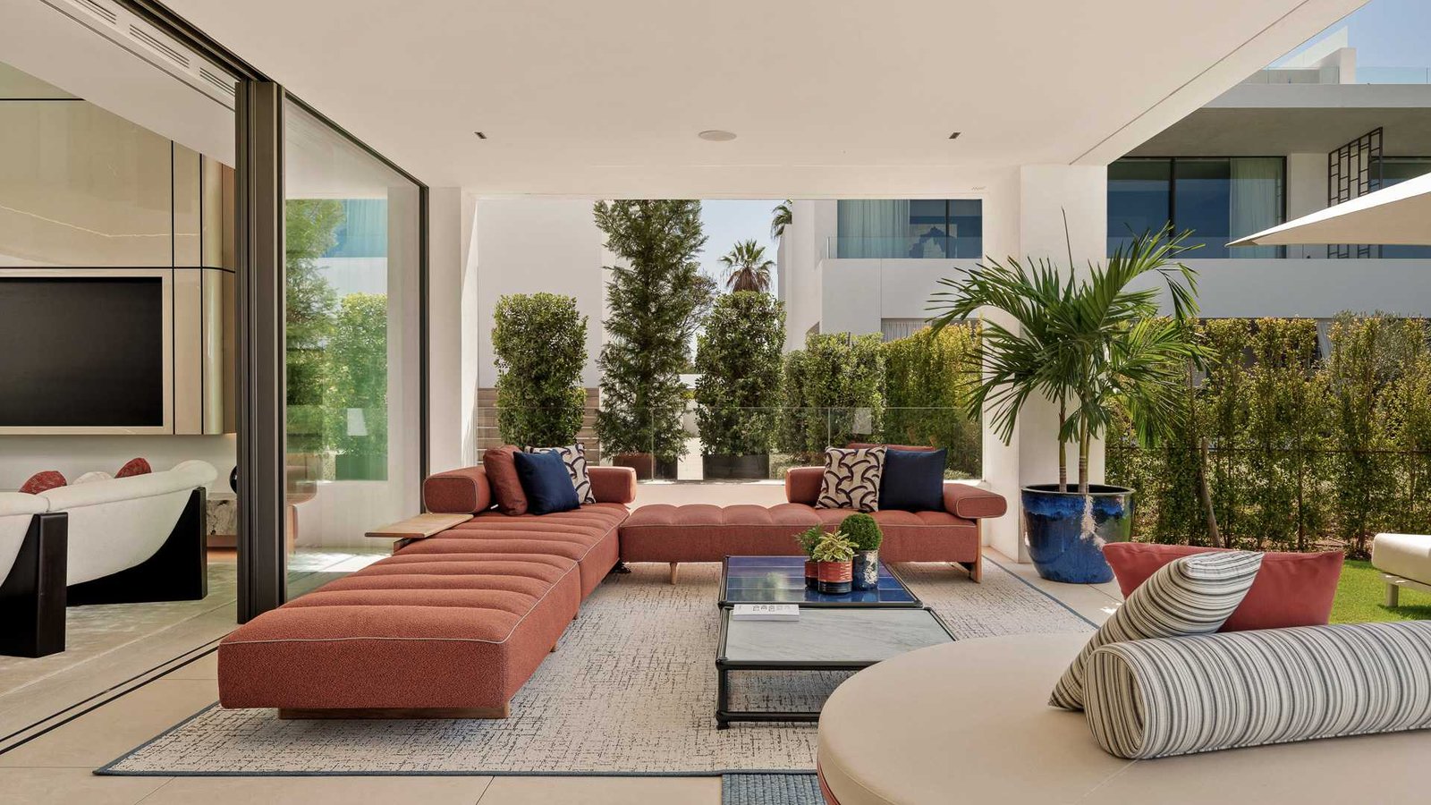 A stylish ground-floor terrace of an exclusive residence near Puente Romano on the Golden Mile, featuring modern outdoor furniture, lush greenery, and elegant stone flooring. The space offers a perfect blend of luxury and comfort, with a peaceful atmosphere and views of the beautifully landscaped surroundings.