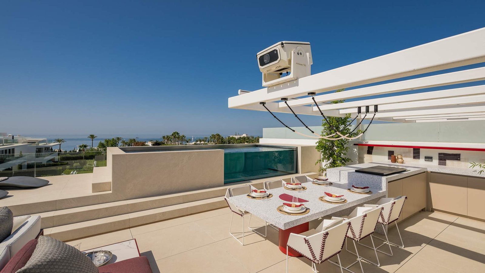 Exquisite solarium with a private pool and outdoor dining area in a luxury residence near Puente Romano on the Golden Mile. The space features sleek modern lounge furniture, a stunning infinity pool, and a stylish dining setup, all framed by breathtaking views and warm ambient lighting, creating the perfect setting for relaxation and entertainment.