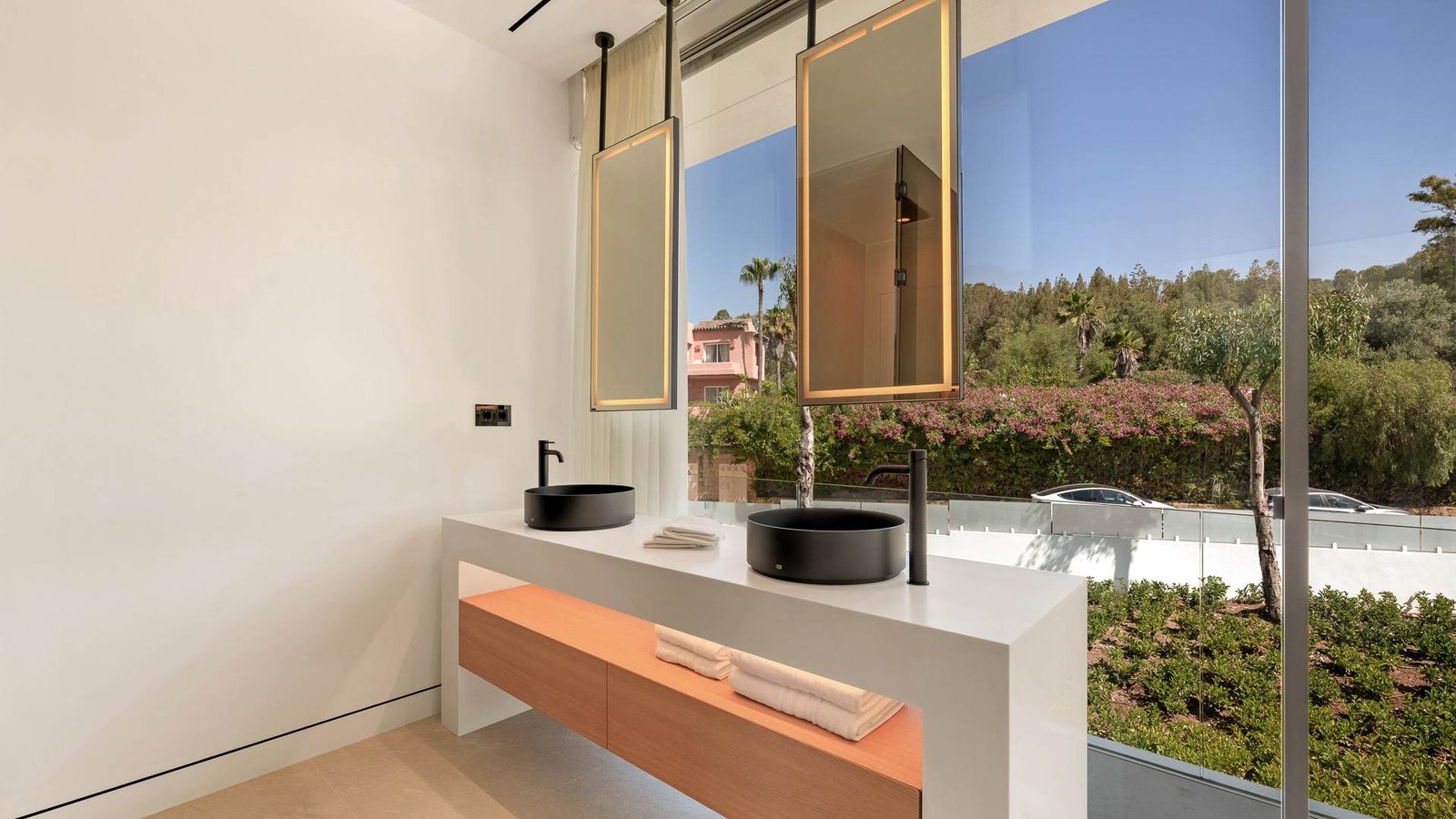 Elegant vanity area in a luxury residence near Puente Romano on the Golden Mile, featuring a sleek floating double sink with a marble countertop, warm ambient lighting, and sophisticated wood accents. The design combines modern minimalism with high-end finishes, creating a serene and stylish bathroom space.