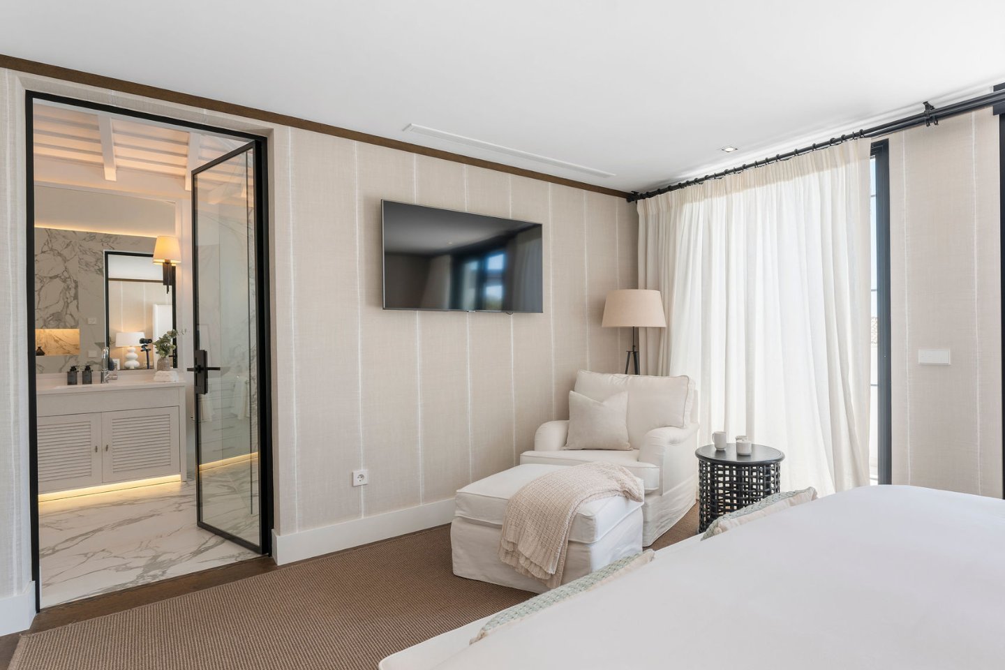 A luxurious bedroom and bathroom combination, featuring a king-size bed with soft, neutral-toned linens and large windows offering stunning views of the golf course. The adjoining bathroom includes a spacious walk-in shower, a freestanding bathtub, and elegant marble finishes, creating a serene and sophisticated retreat.
