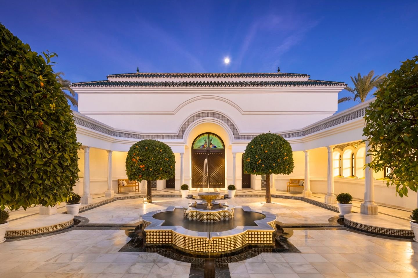 Beautiful courtyard in a majestic Andalusian palace in Marbella, featuring lush greenery, intricate tilework, and elegant arches that frame a tranquil outdoor space, offering a serene and timeless retreat surrounded by the palace's architectural splendor.