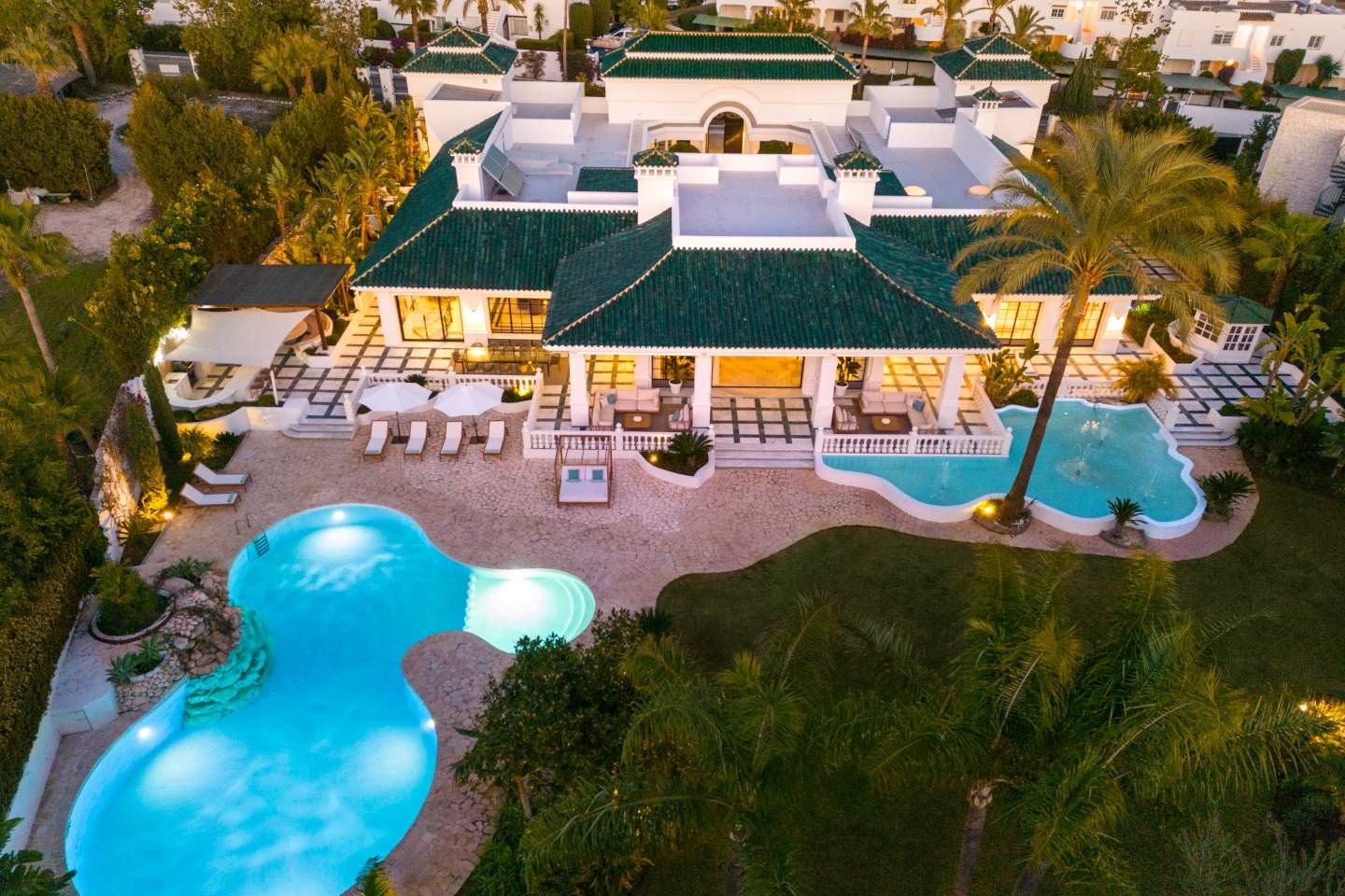 Impressive facade of a majestic Andalusian palace in Marbella, showcasing intricate architectural details, grand arches, and lush greenery, blending classic Andalusian style with modern luxury, reflecting the timeless beauty and elegance of the property.
