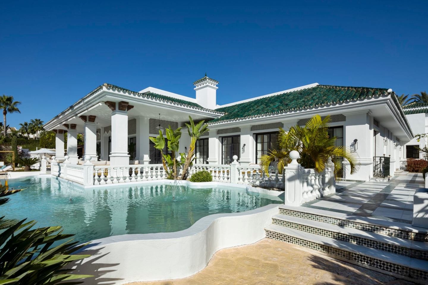 Breathtaking pool area in a majestic Andalusian palace in Marbella, featuring an expansive outdoor space with elegant arches, lush gardens, and tranquil water, offering a luxurious setting for relaxation and entertaining amidst timeless architectural beauty.