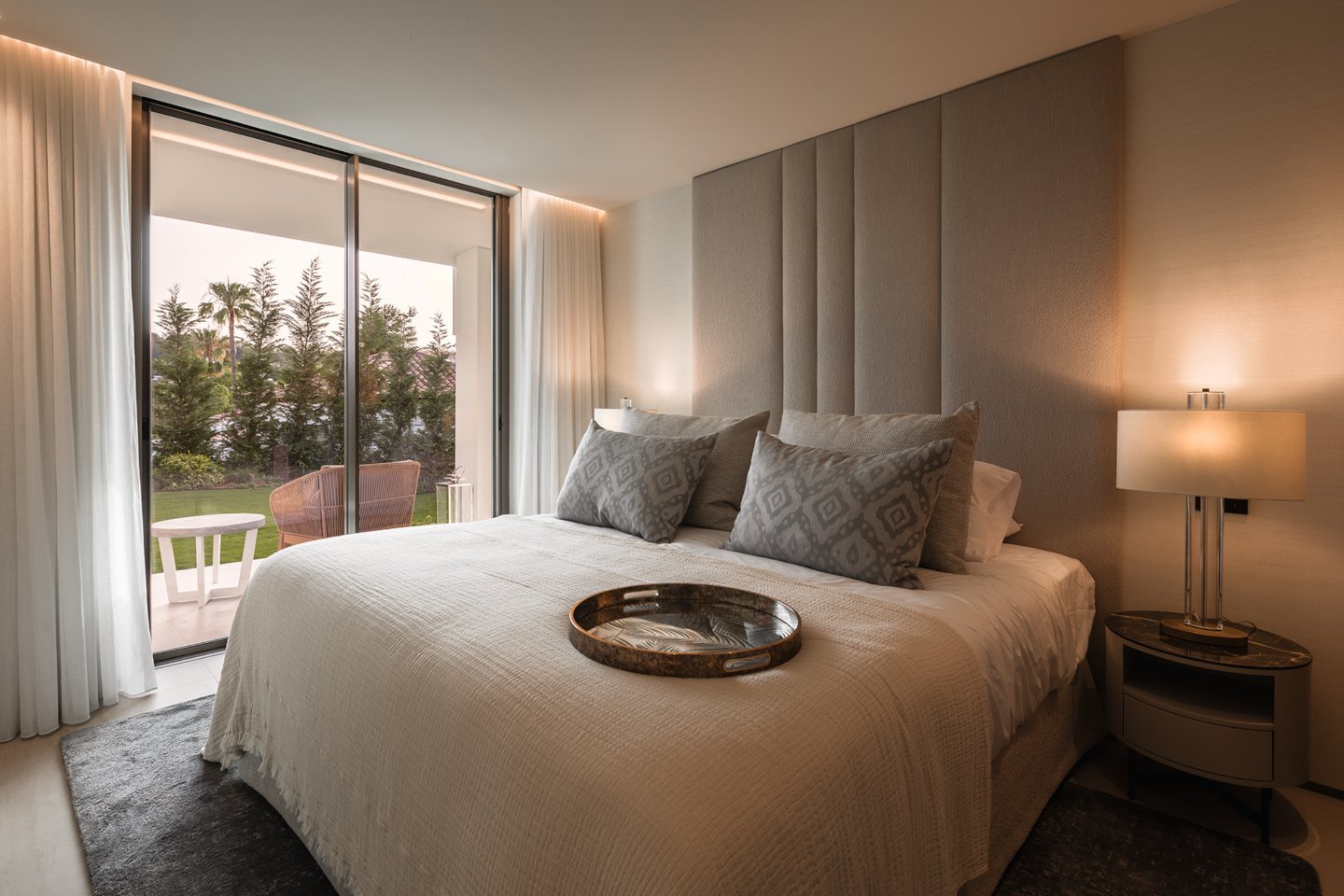 Sophisticated bedroom in a modern villa in Nueva Andalucía, featuring minimalist furniture, soft neutral tones, and large windows that allow natural light to create a serene atmosphere. The sleek design combines comfort and luxury, with elegant finishes and a calm, inviting space perfect for rest and relaxation.