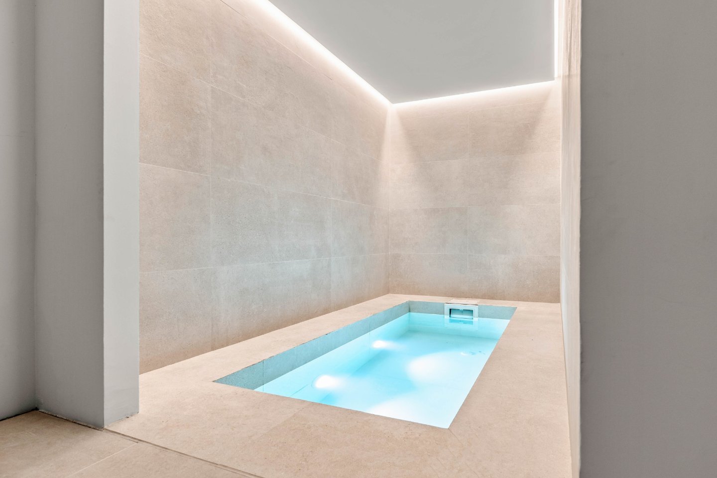 A stunning indoor pool area featuring crystal-clear water, surrounded by sleek stone flooring and large glass walls that offer views of the villa's lush surroundings. Soft lighting and elegant decor create a serene, spa-like atmosphere, blending luxury with Provencal charm.