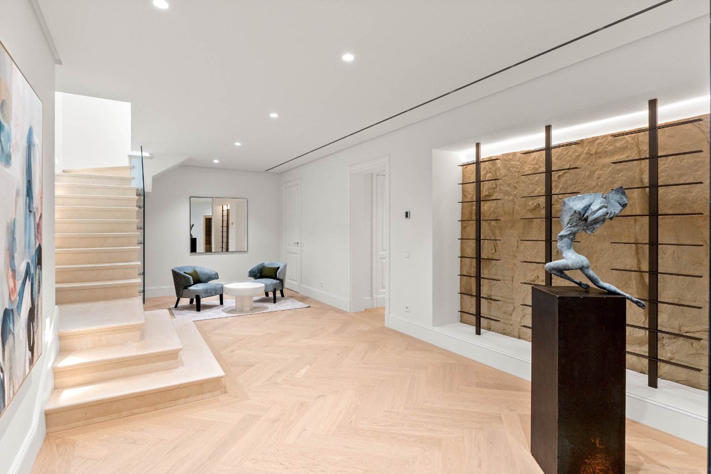 A beautifully designed stairway featuring elegant wrought-iron railings and polished marble steps, leading to the upper levels of a luxurious villa. The space is bathed in natural light, with large windows that highlight the refined Provencal-inspired details and warm, inviting atmosphere.