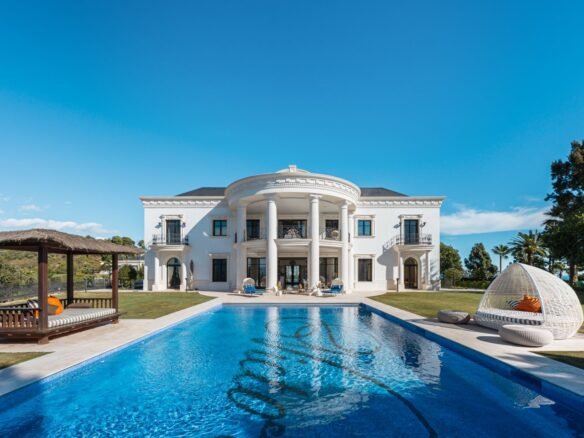 Stunning facade of a luxury villa in Las Chapas, Marbella, showcasing elegant architectural design with clean lines, large windows, and a harmonious blend of modern and classic elements. Surrounded by lush greenery, the villa exudes timeless elegance and exclusivity, offering a perfect balance of sophistication and natural beauty.