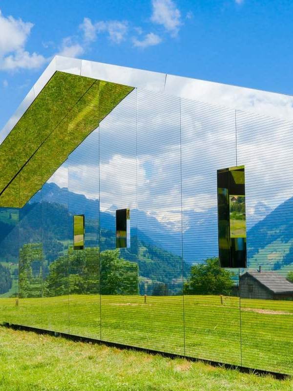 A modern sustainable luxury villa surrounded by lush greenery, featuring sleek architectural design, large glass windows, and eco-friendly elements. The property seamlessly integrates nature with contemporary living, offering a harmonious blend of elegance and sustainability.